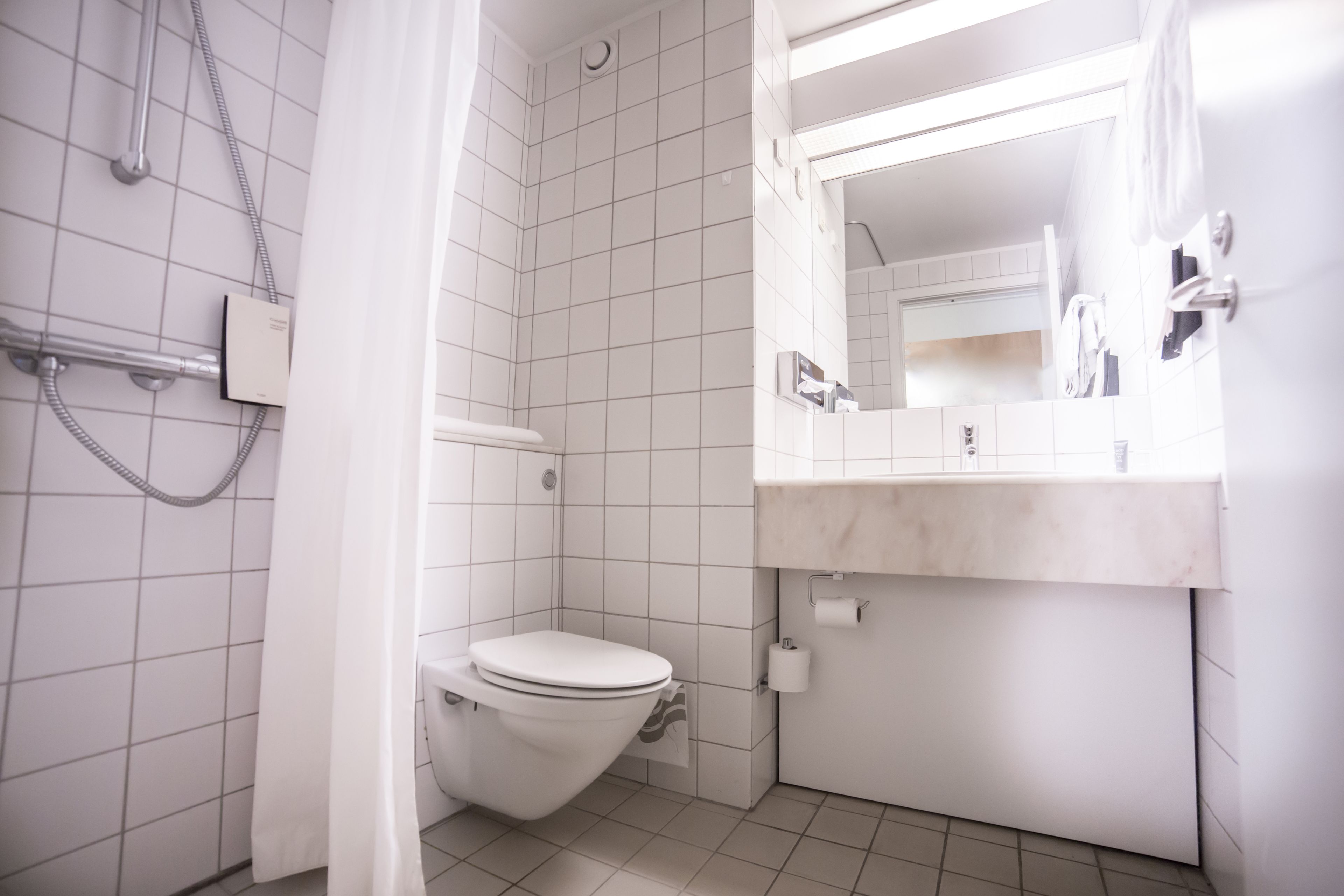 A small, modern bathroom with a toilet, shower, and sink.