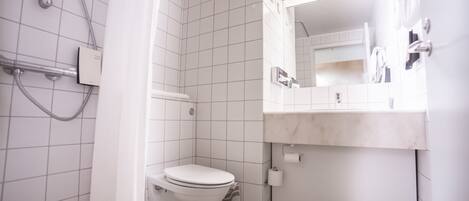 A small, modern bathroom with a toilet, shower, and sink.