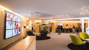 A modern reception area with a large digital display, seating arrangements, and a brick wall. - Comwell Rebild Bakker (Skorping)