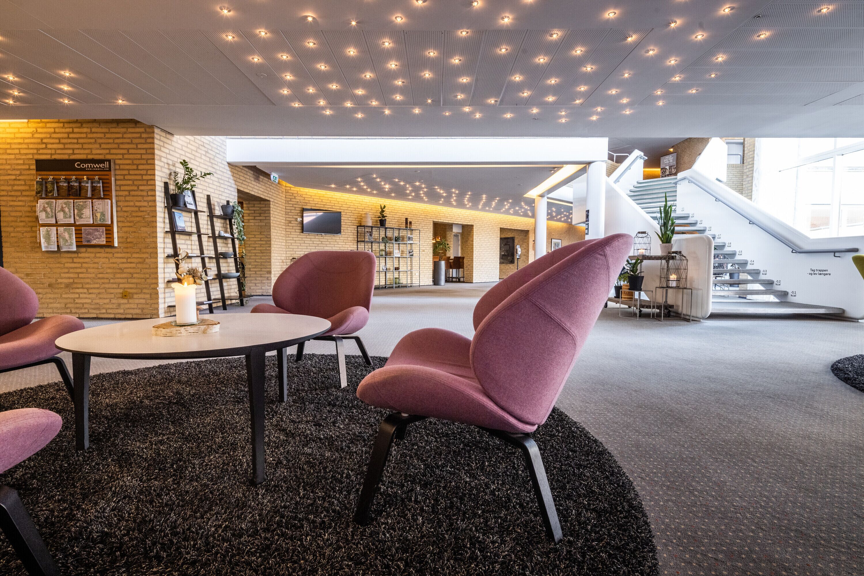 En moderne lobby med tæppe, trappe og en reception med skiltet "Comwell".