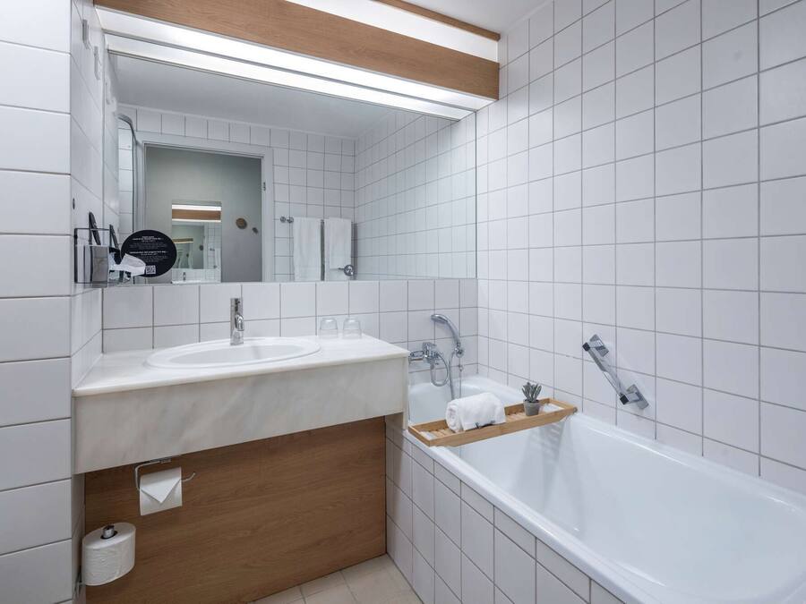 A modern bathroom with two sinks, a large mirror, and a bathtub.