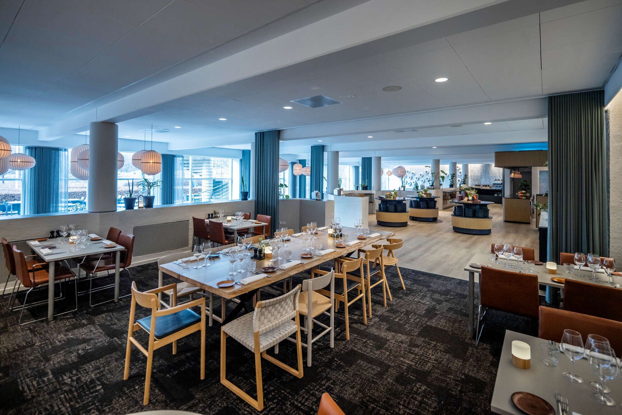 A spacious restaurant with multiple dining areas, large windows, and modern decor.