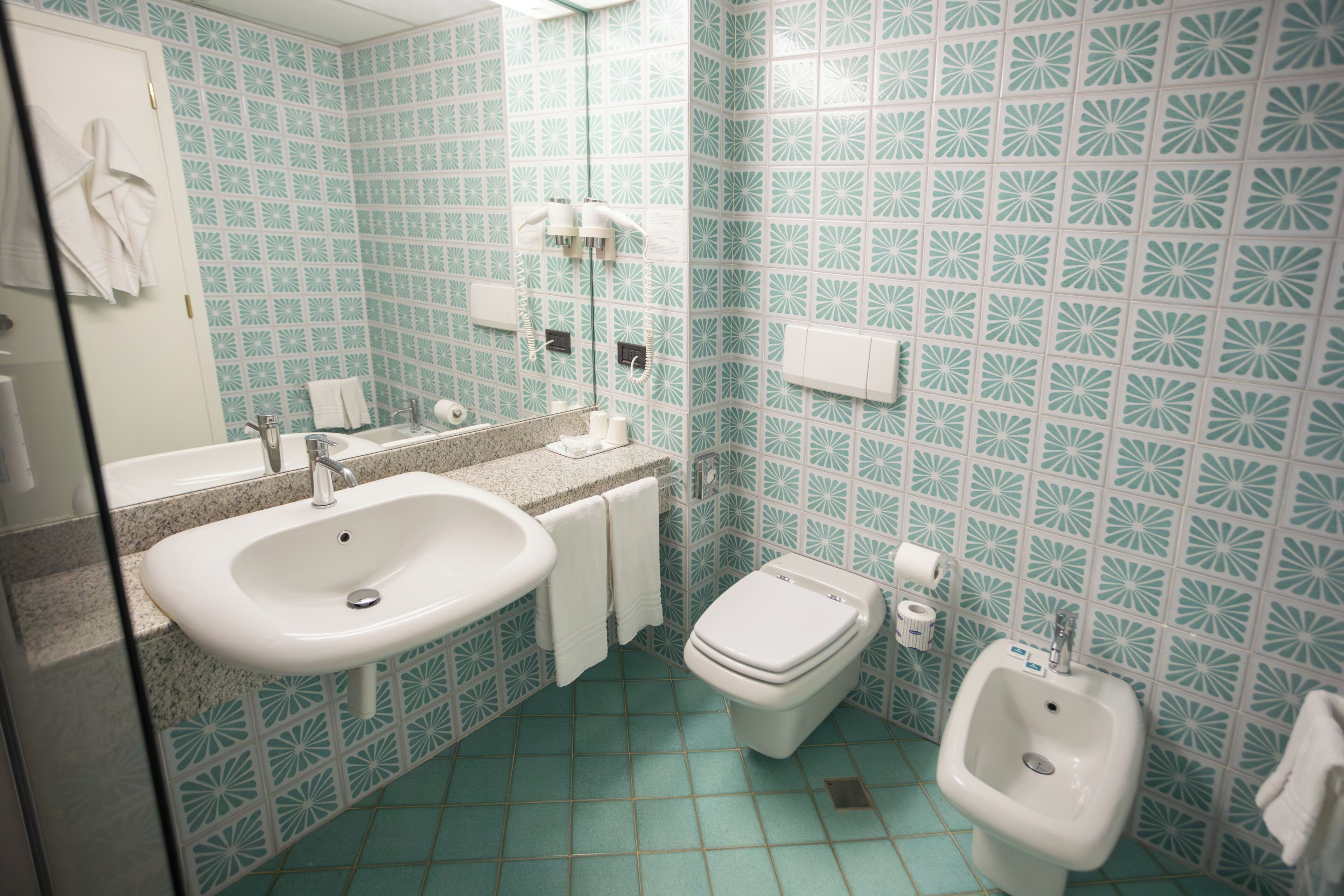 Une salle de bain équipée d’un lavabo, de toilettes, d’un bidet et d’un miroir.