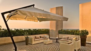 A rooftop terrace with outdoor seating, a large umbrella, and a view of the sea. - Grand Hotel Terme (Margherita di Savoia)