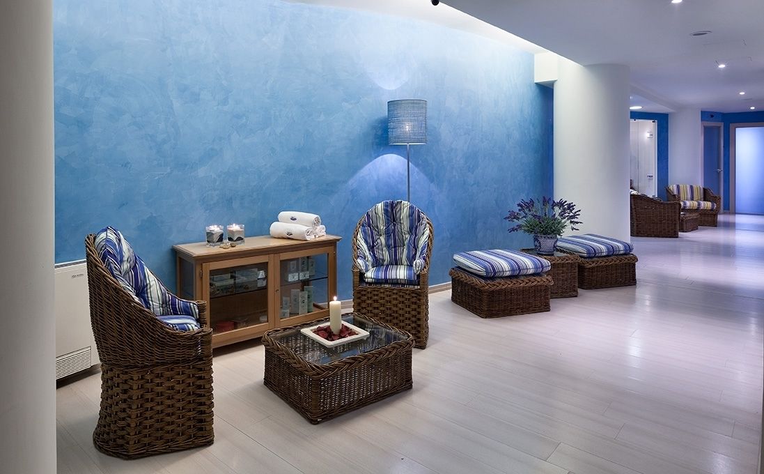 Eine moderne Lobby mit Korbmöbeln, einem Glastisch mit Kerze und einer blauen Wand.