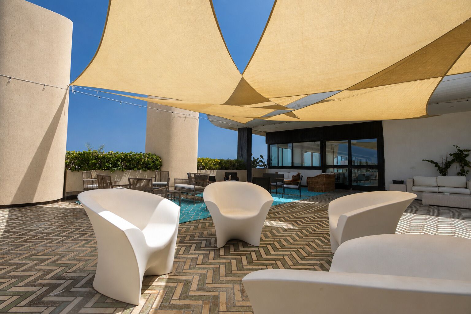 A rooftop terrace with outdoor seating, a pool, and a view of the city skyline.