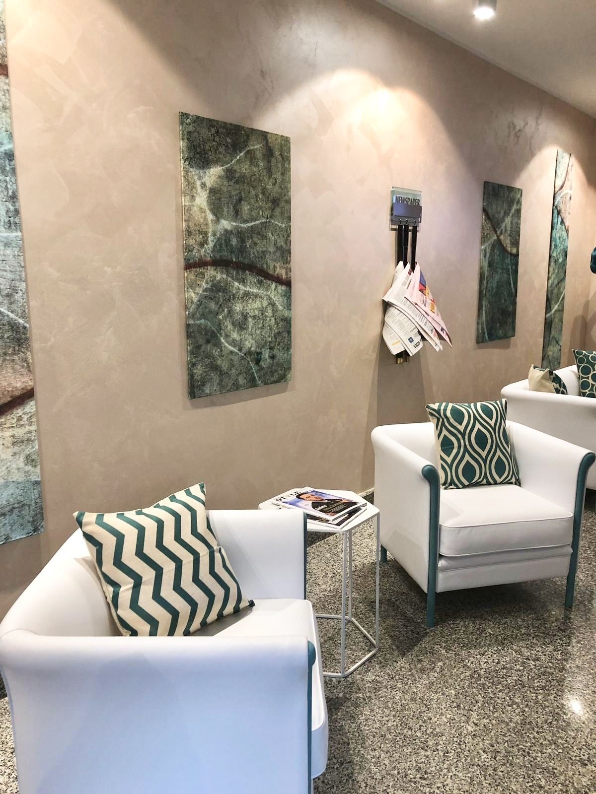 A modern interior with a white armchair, a small table with a magazine, and abstract wall art.