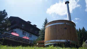 A wooden structure with a chimney, a building with balconies, and outdoor seating with umbrellas. - Blue Mountain Hotel (Treffen)