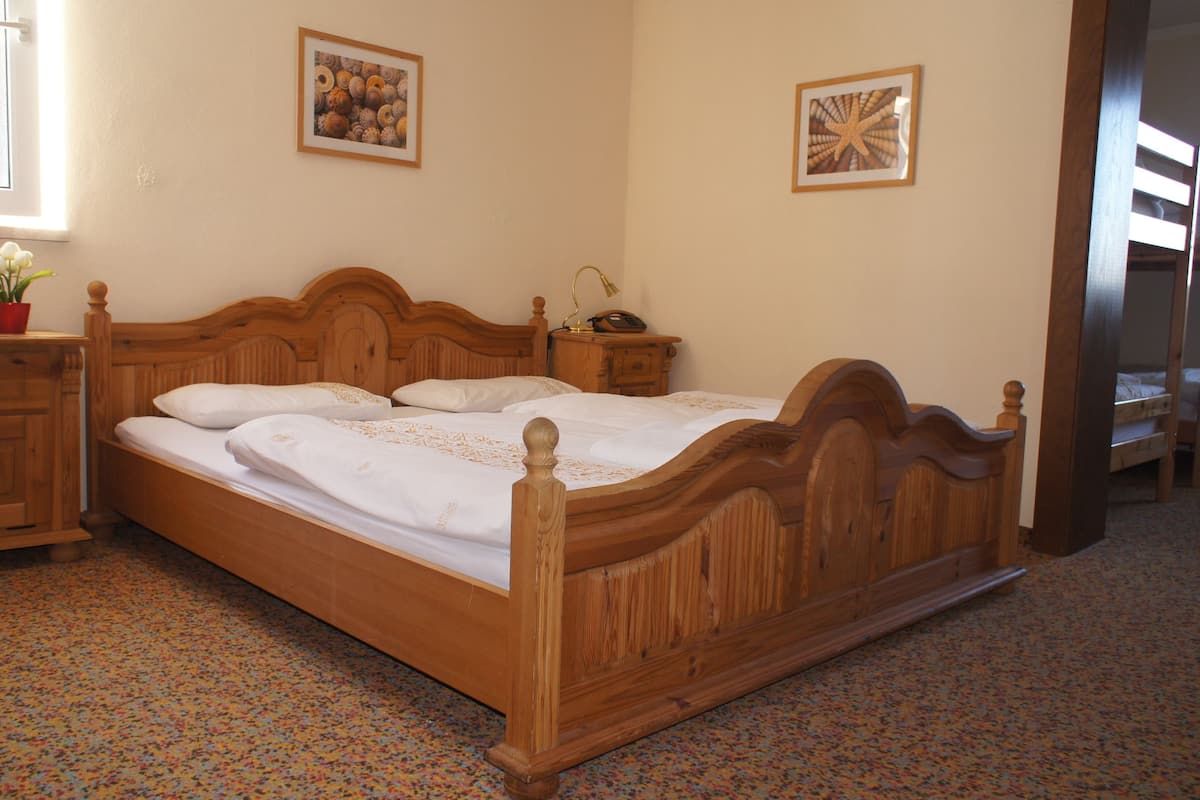 A wooden bed with a headboard, a bedside table with a lamp, and two framed pictures on the wall.