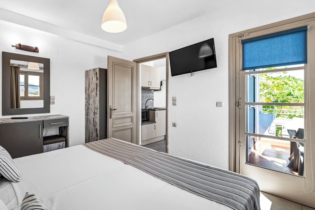 Une chambre à coucher comprenant un lit, une table de chevet, une lampe et un téléviseur fixé au mur.