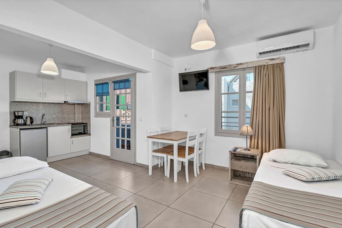 Une chambre d’hôtel moderne dotée d’une kitchenette, d’un coin repas et de deux lits.