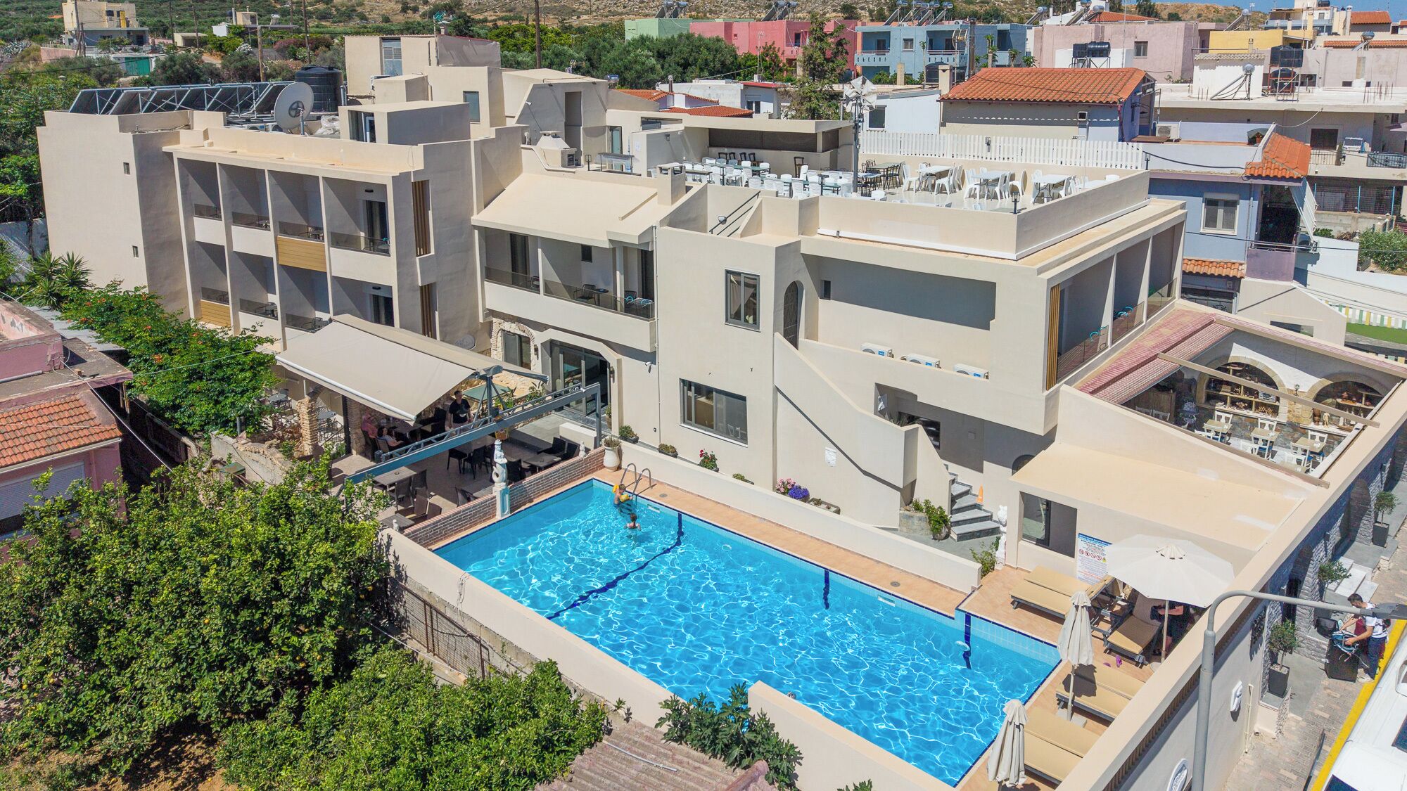 A modern building with a rooftop pool, multiple balconies, and a flat roof design.