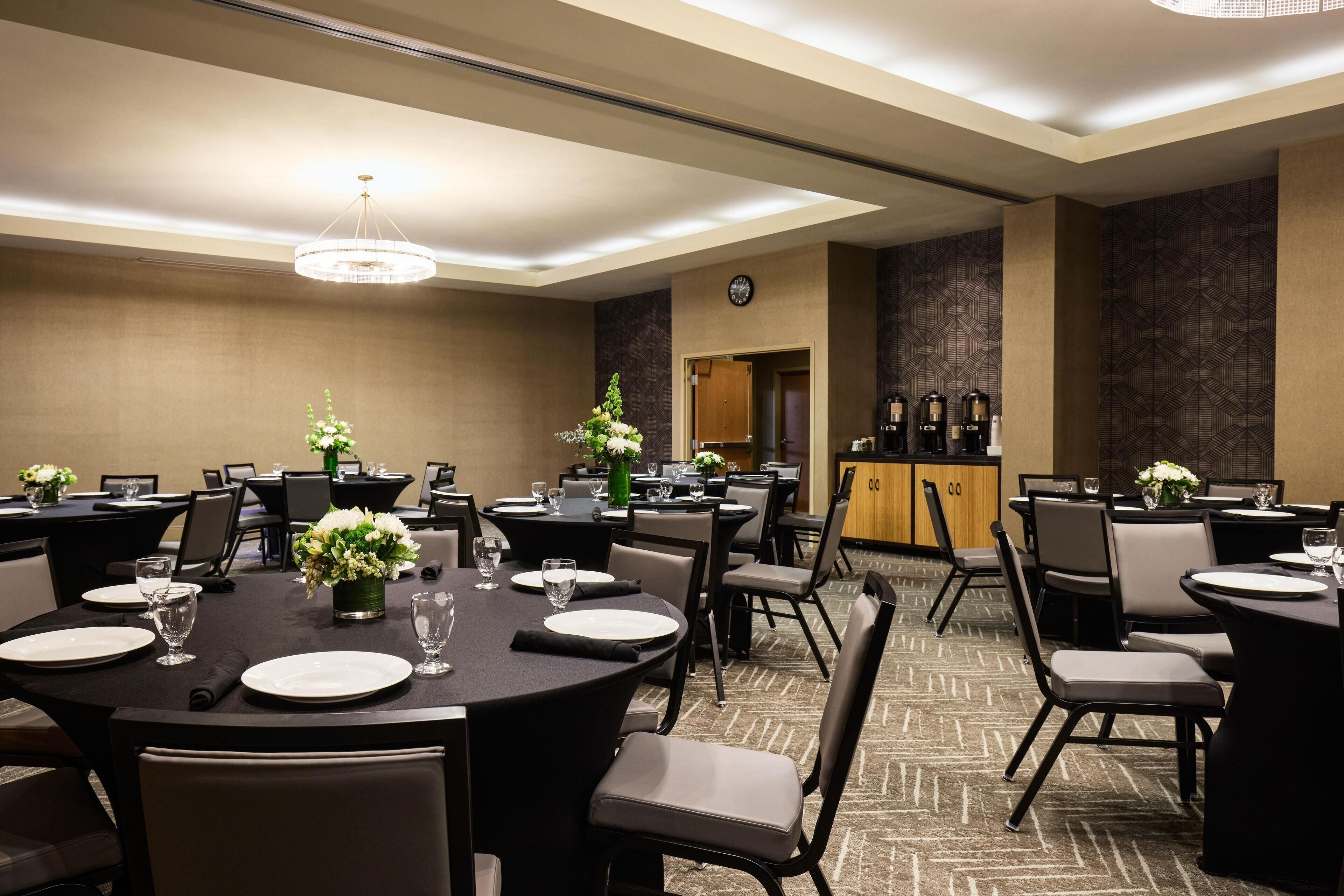 A conference room with round tables, chairs, and a clock on the wall.