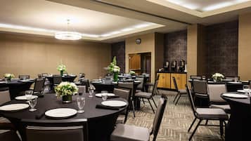 A conference room with round tables, chairs, and a clock on the wall.
