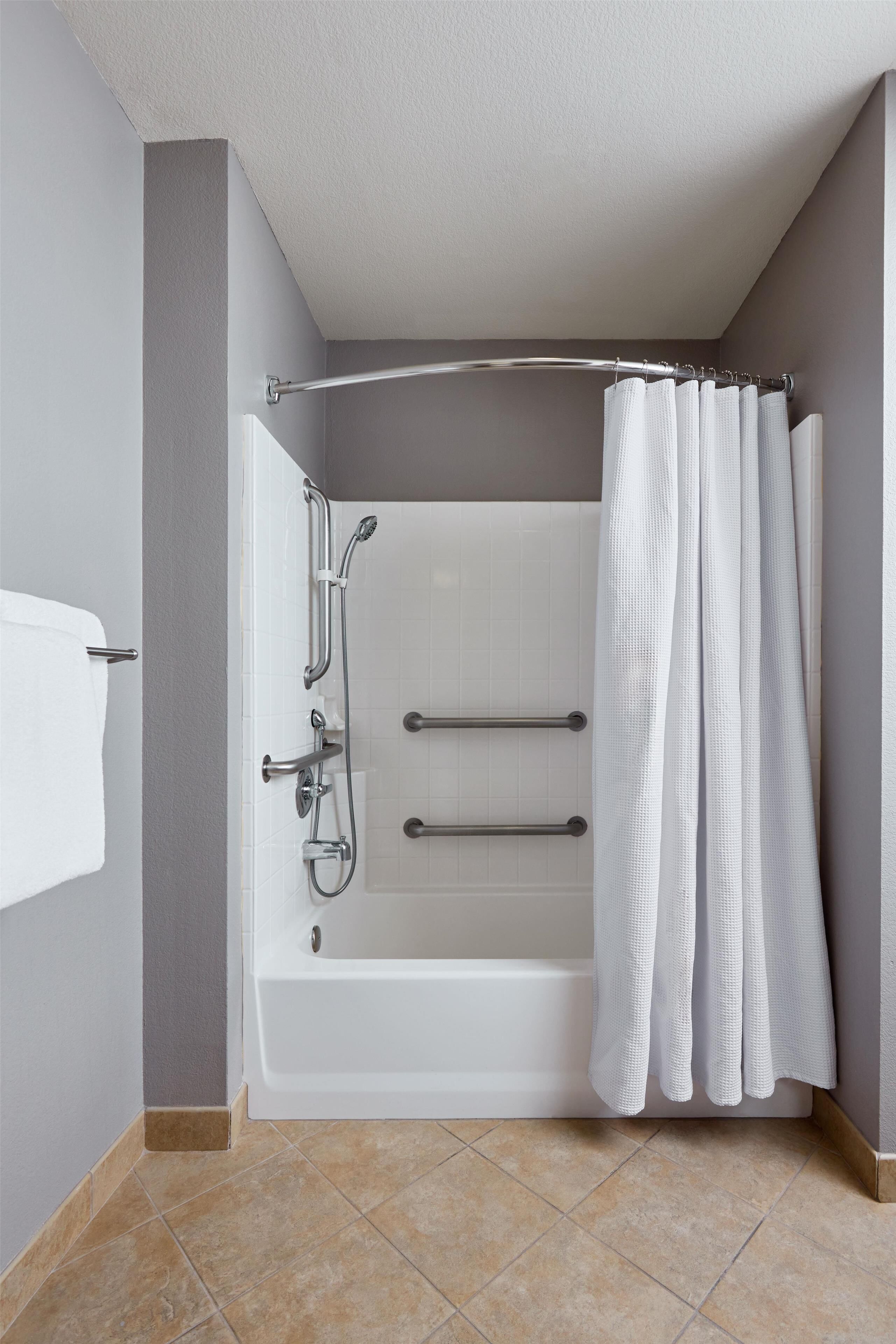 Une salle de bain équipée d’une baignoire, d’une douche et de barres d’appui.