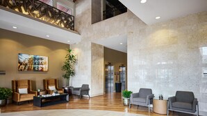 A spacious lobby with a high ceiling, marble walls, and a central seating area with sofas and a coffee table. - Hyatt House Seattle/Bellevue (Bellevue)