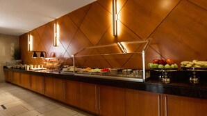 A buffet area with a wooden panel wall, a glass food display, and a variety of fruits and vegetables. - Hyatt House Seattle/Bellevue (Bellevue)