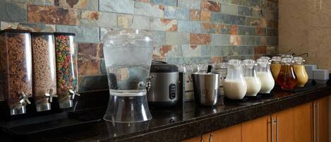 A kitchen with a stone backsplash, a water dispenser, and various food containers.