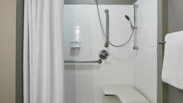 Un espace douche avec un rideau de douche blanc, une douchette à main et un banc.