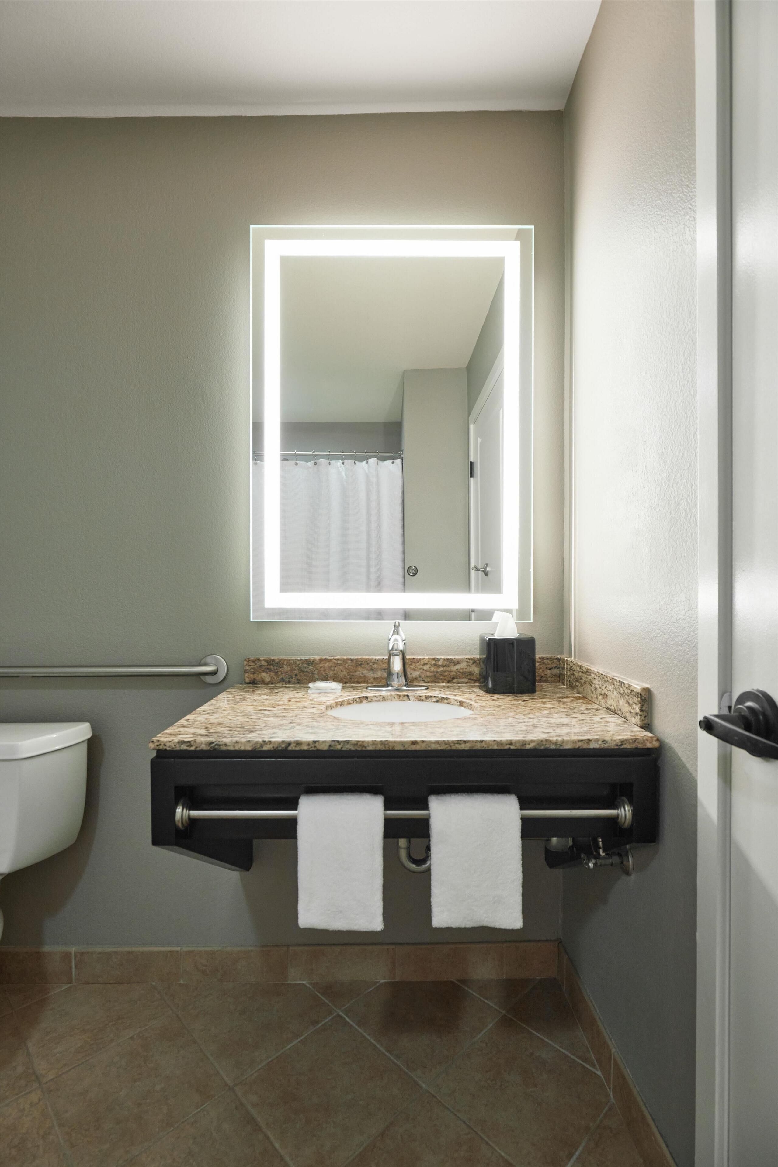 A bathroom with a sink, mirror, and towel rack.