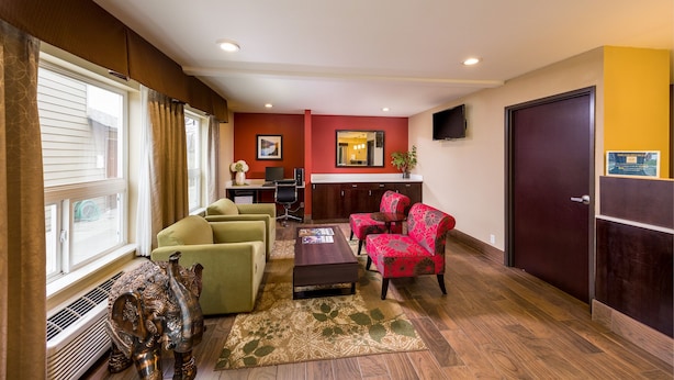 A living room with a sofa, armchair, and a coffee table. There is a kitchen area with a counter and cabinets in the background. - Sunset Motel Hood River (Hood River)