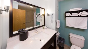 A modern bathroom with a white sink, a large mirror, a hairdryer, and a shelf with towels. - Sunset Motel Hood River (Hood River)