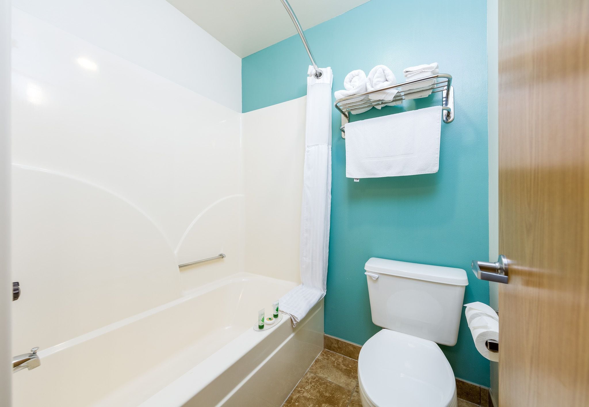 Een badkamer met een bad, toilet en handdoekrek.