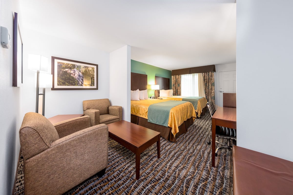 A hotel room with a bed, two bedside tables, a sofa, a desk, and a lamp.