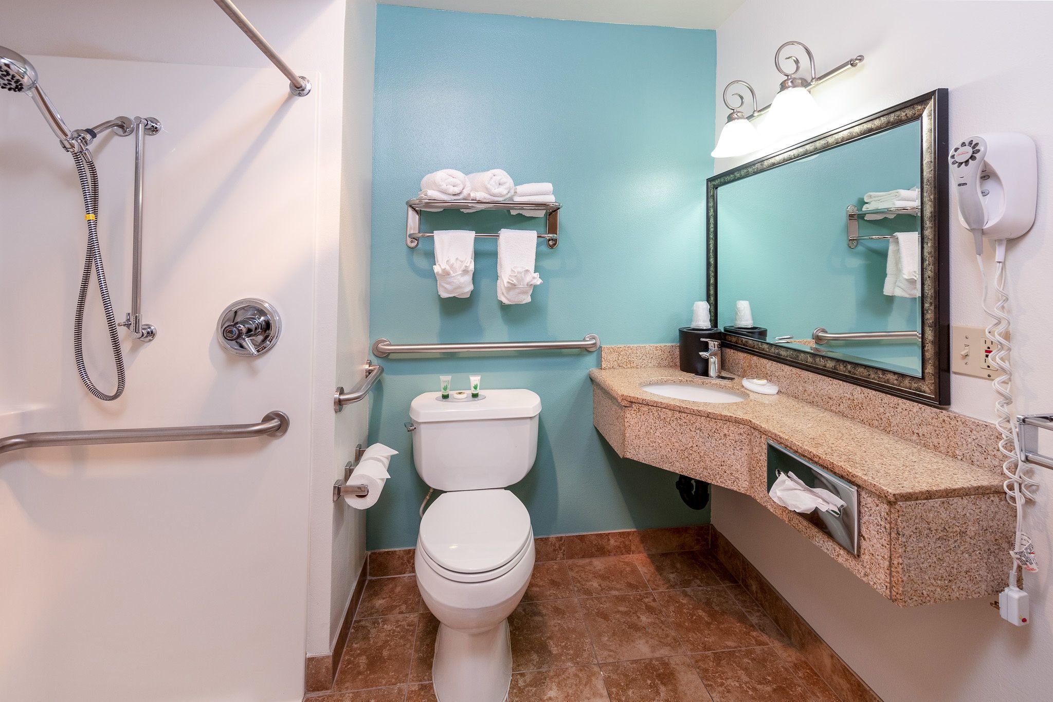 A bathroom with a shower, toilet, sink, and towel rack.