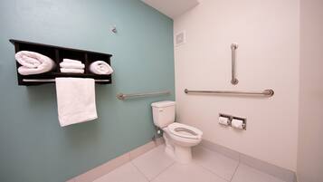 A bathroom with a teal wall, a white toilet, a towel rack with folded towels, and a grab bar.