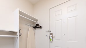 A white room with a closet, a hanging towel, and a door. - Sunset Motel Hood River (Hood River)