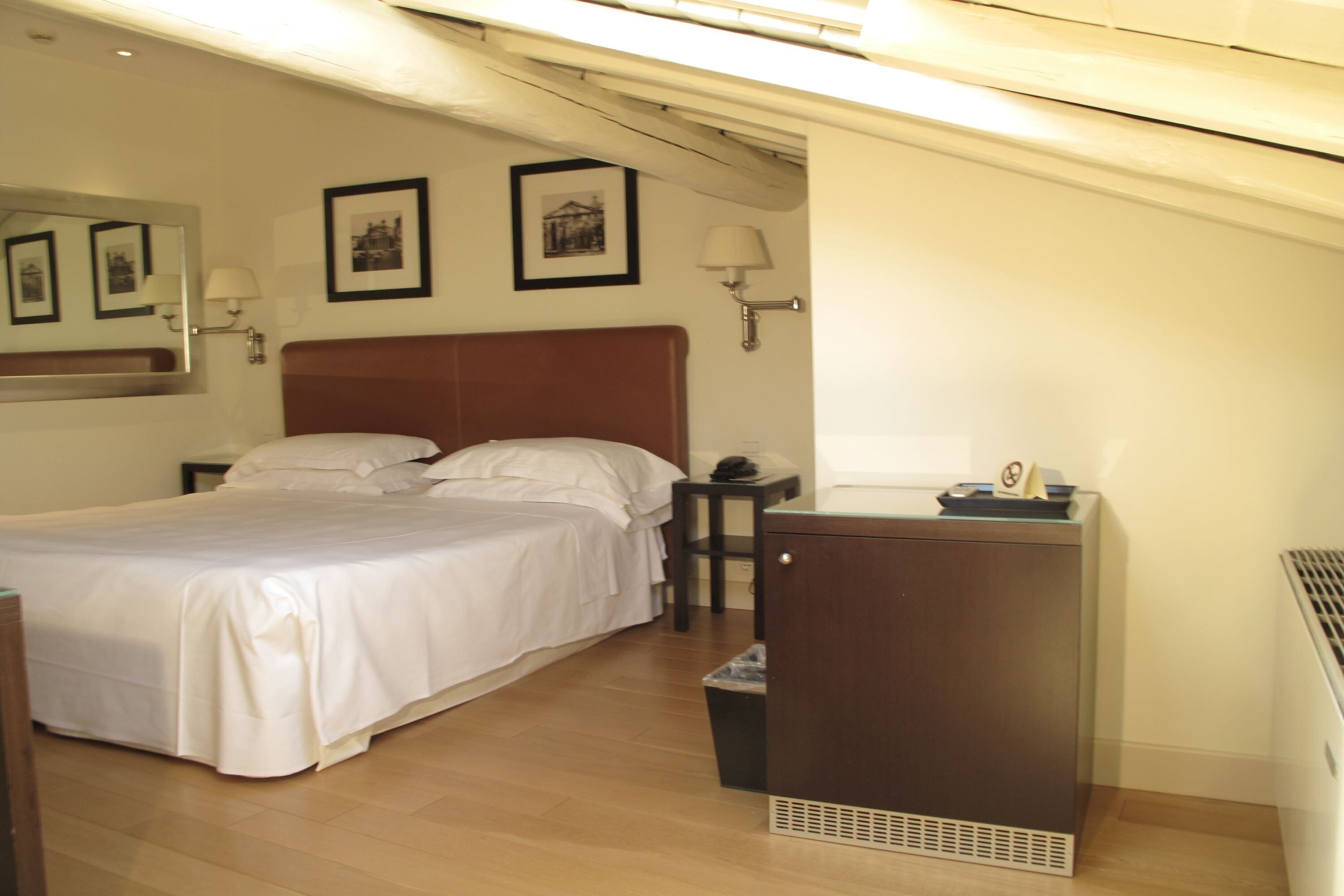 A bedroom with a bed, a nightstand, a desk, and a dresser.