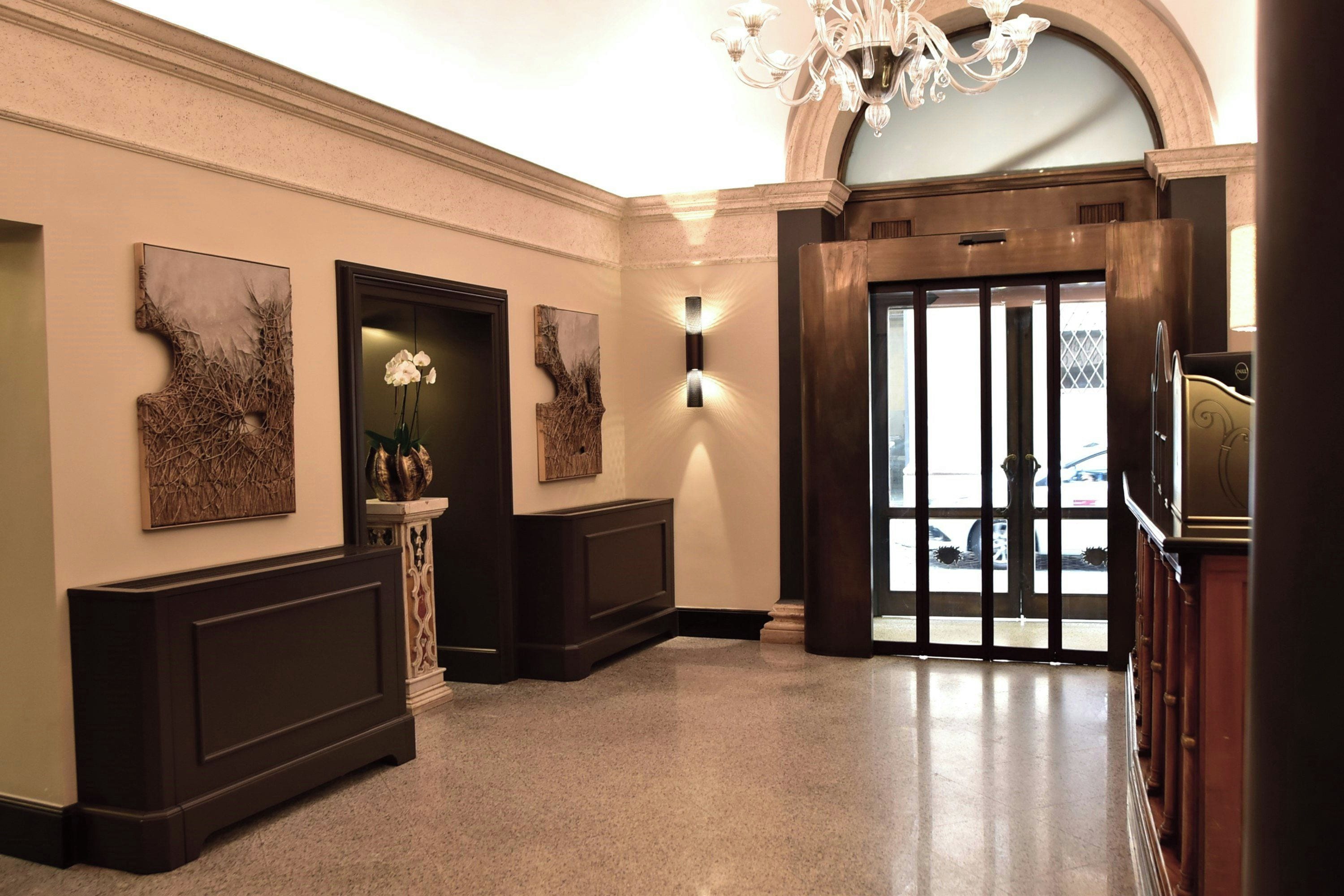 A hotel lobby with a grand entrance, wall-mounted artwork, and a chandelier.