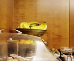 A kitchen counter with a bowl of bananas and a glass container.
