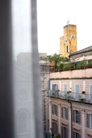 Una vista di un edificio con una torre, balconi dotati di ringhiere e piante in vaso.