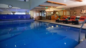 Une piscine avec des chaises longues et un espace bar.