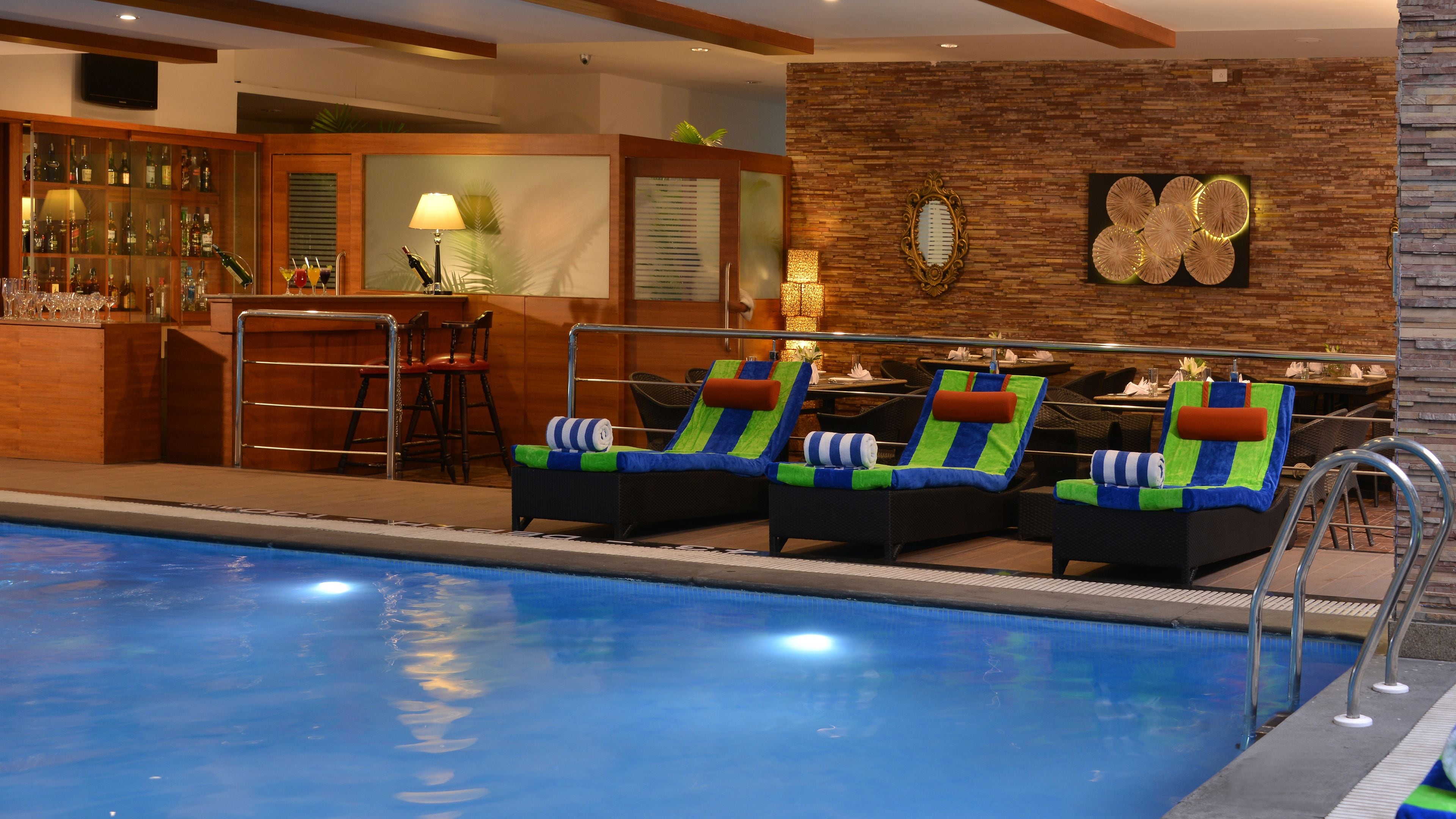 Un área junto a la piscina con sillones de descanso, un bar y un comedor.