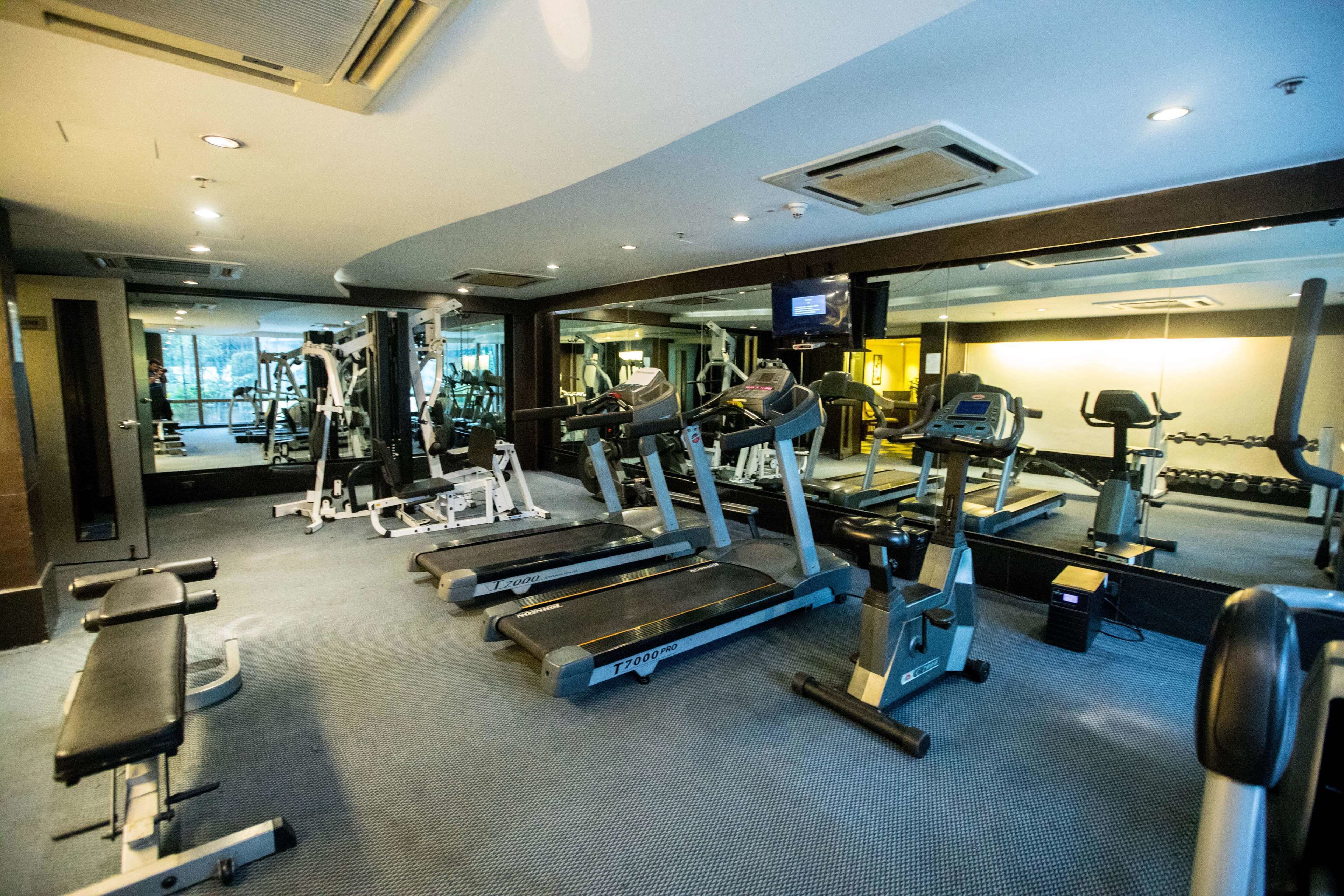A gym with treadmills, weight machines, and a mirror reflecting the equipment.