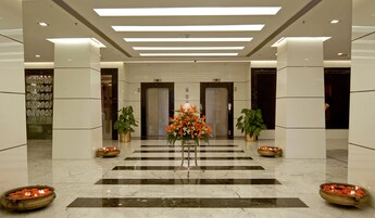 A lobby with a marble floor, two potted plants, a floral arrangement, and two bowls of flowers.