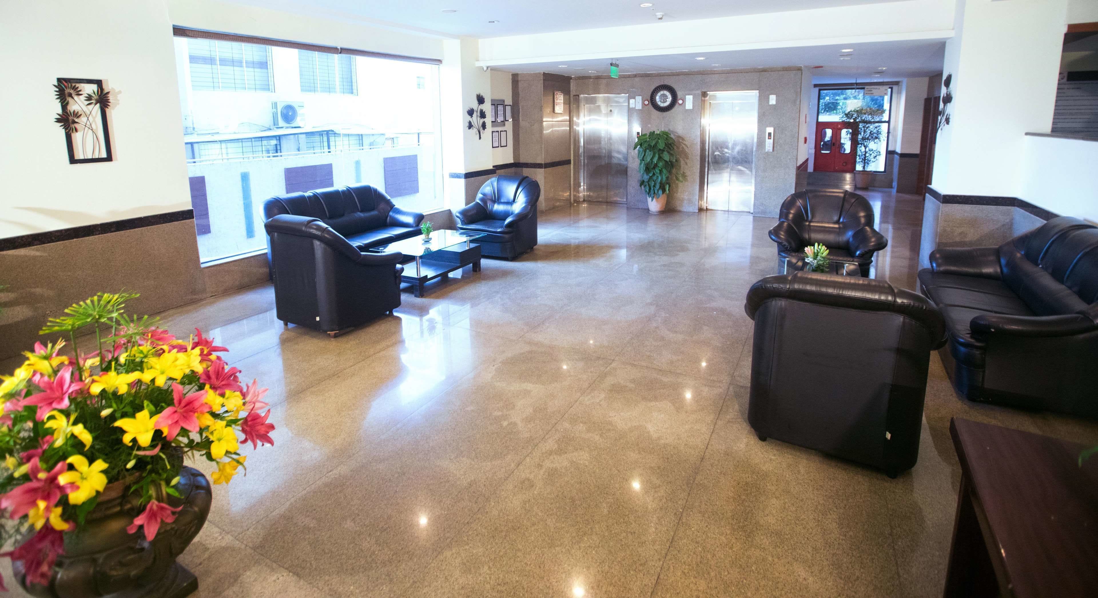 Um hall amplo com sofás de couro, uma mesa de centro e um vaso de plantas.