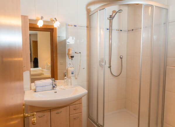 Un baño con ducha, lavamanos y espejo.