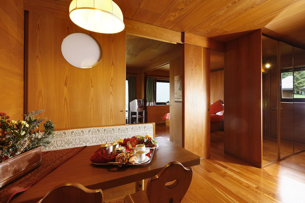 A wooden dining table with a tray of food, a vase of flowers, and a bench.