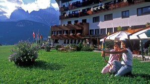 A hotel with multiple balconies, outdoor seating, and a mountain backdrop. - Hotel Mirage (Cortina d'Ampezzo)