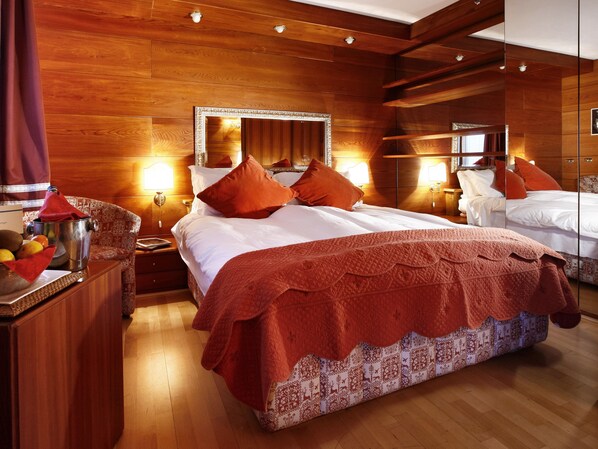 A hotel room with a large bed, wooden paneling, and a mirror above the bed.