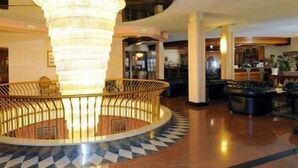 A lobby with a central circular seating area, a chandelier, and a checkered floor pattern. - Park Hotel Oasi (Garda)