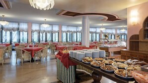 A buffet setup with multiple tables, chairs, and a variety of food items. - Park Hotel Oasi (Garda)