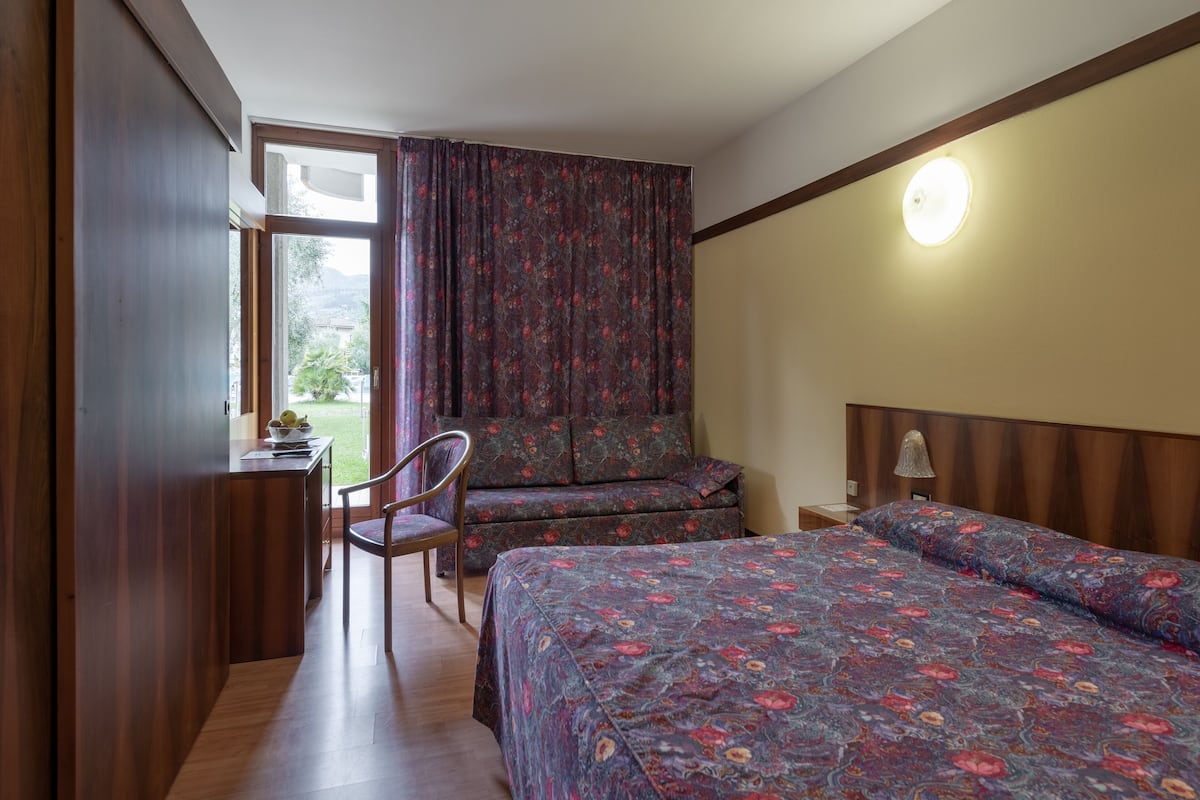 Ein Schlafzimmer mit Bett, Schreibtisch, Stuhl und einem Fenster mit Vorhängen.