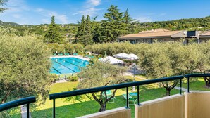 A pool area with a clear view of the surrounding landscape, including trees and distant buildings. - Park Hotel Oasi (Garda)