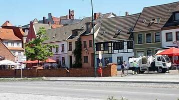 A street view with traditional European buildings, a clear sky, and a parked van.