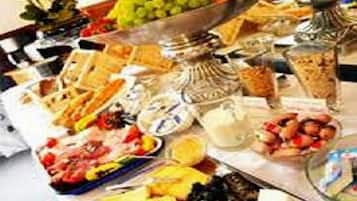 A buffet table with various food items including fruits, cheeses, and breads.